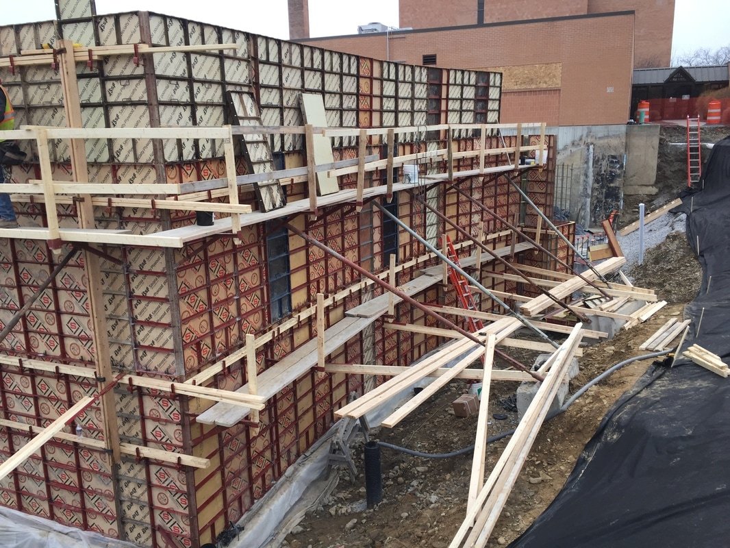 Tall braced wall forms against a brick building